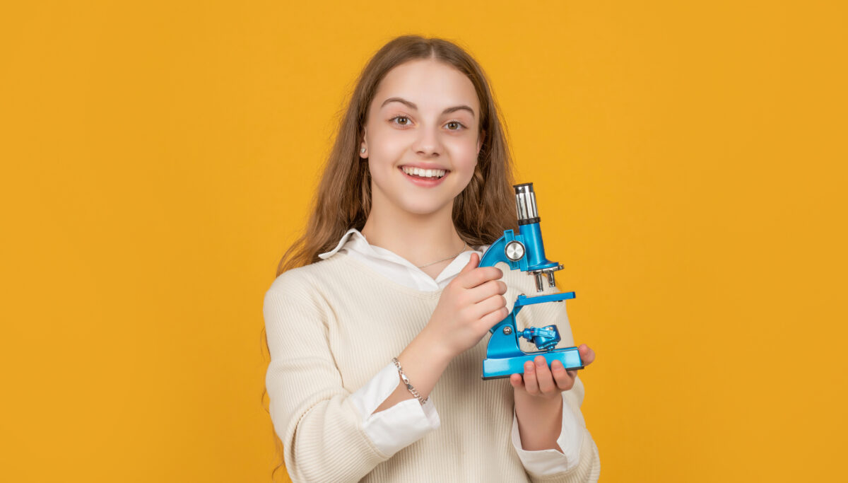 happy amazed child with microscope on yellow background.