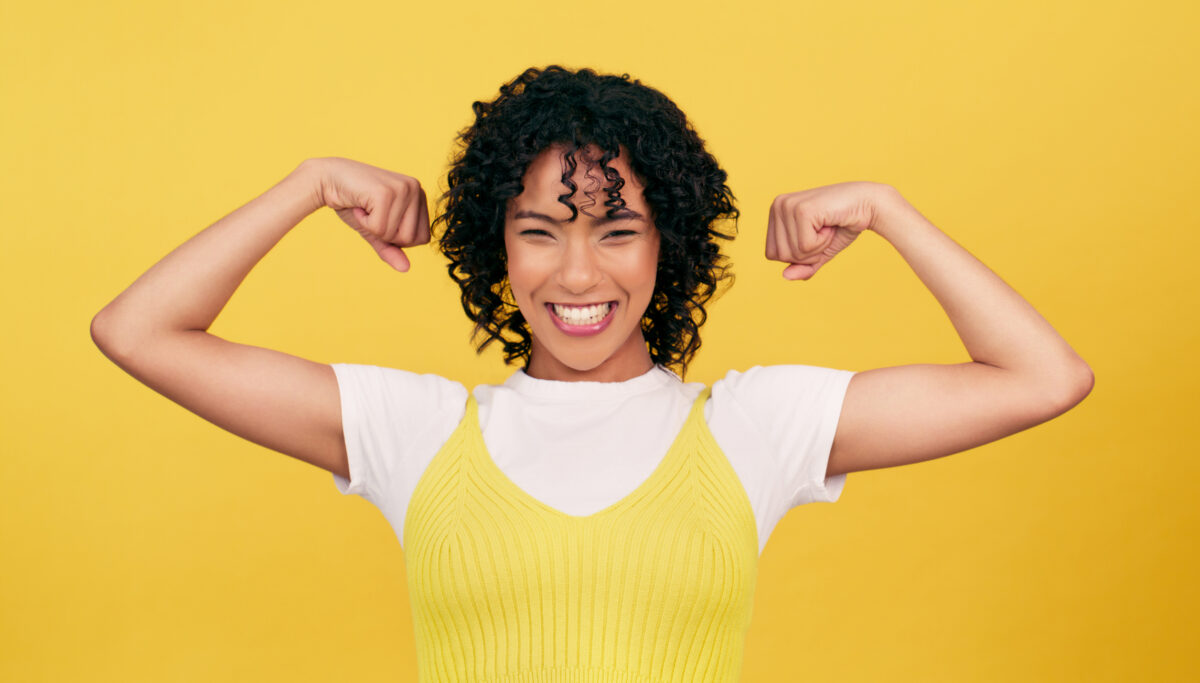 Portrait, happy and woman flex muscle in studio isolated on a yellow background mockup space. Smile, strong girl and bicep arm for power, empowerment of confident young model and energy for feminism