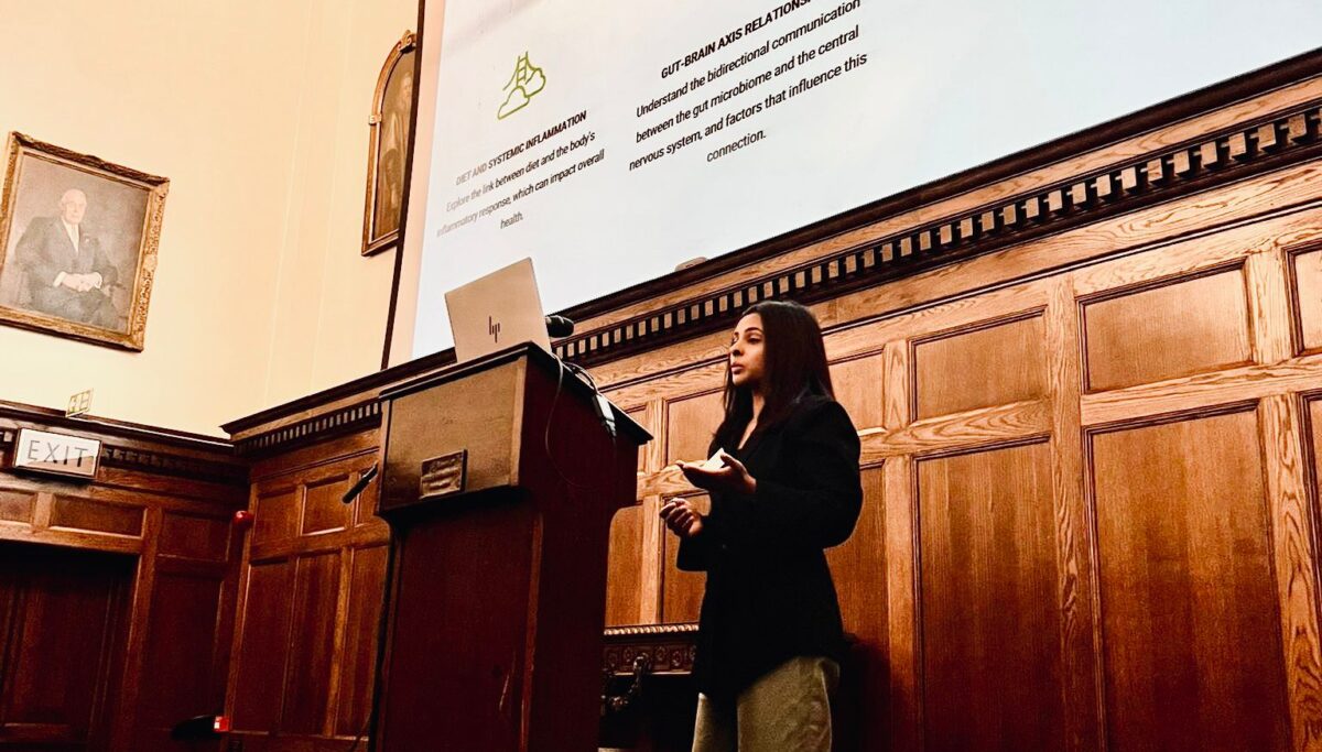 Photo of Amrita, our Lead Scientific Advisory Board member. Standing at podium presenting results from Chuckling Goats study. Female scientist.