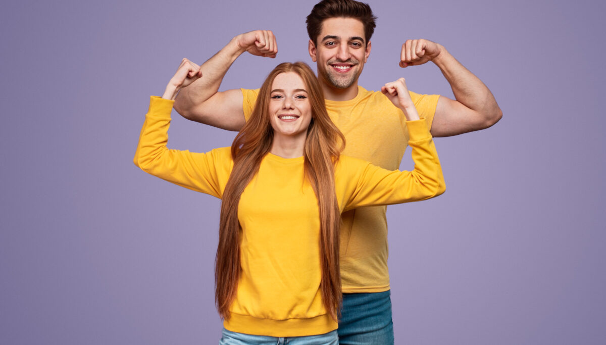 Cheerful young couple flexing muscles
