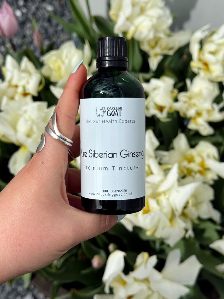 Image of Chuckling Goat Siberian Ginseng Premium tincture held in front of flowers.