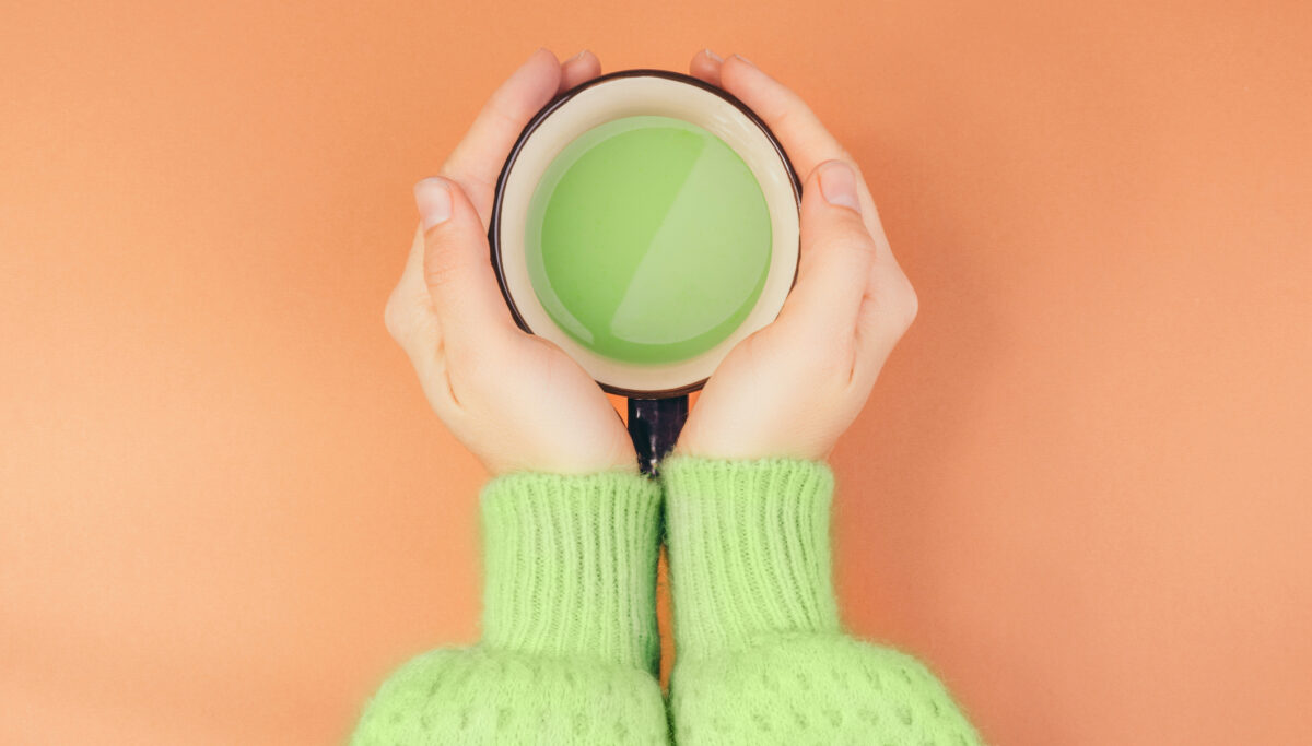 Female hands holding cup of green japanese matcha tea with milk. Organic product.