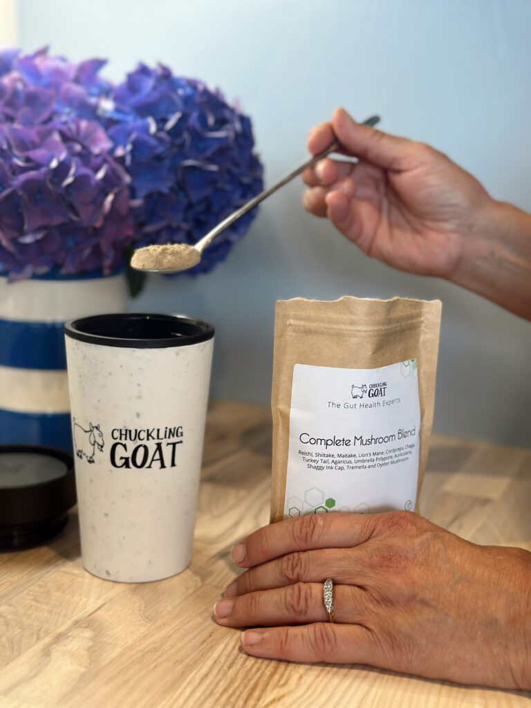 Image of Chuckling Goat Mushroom Powder being added to Chuckling Goat branded travel mug containing coffee.