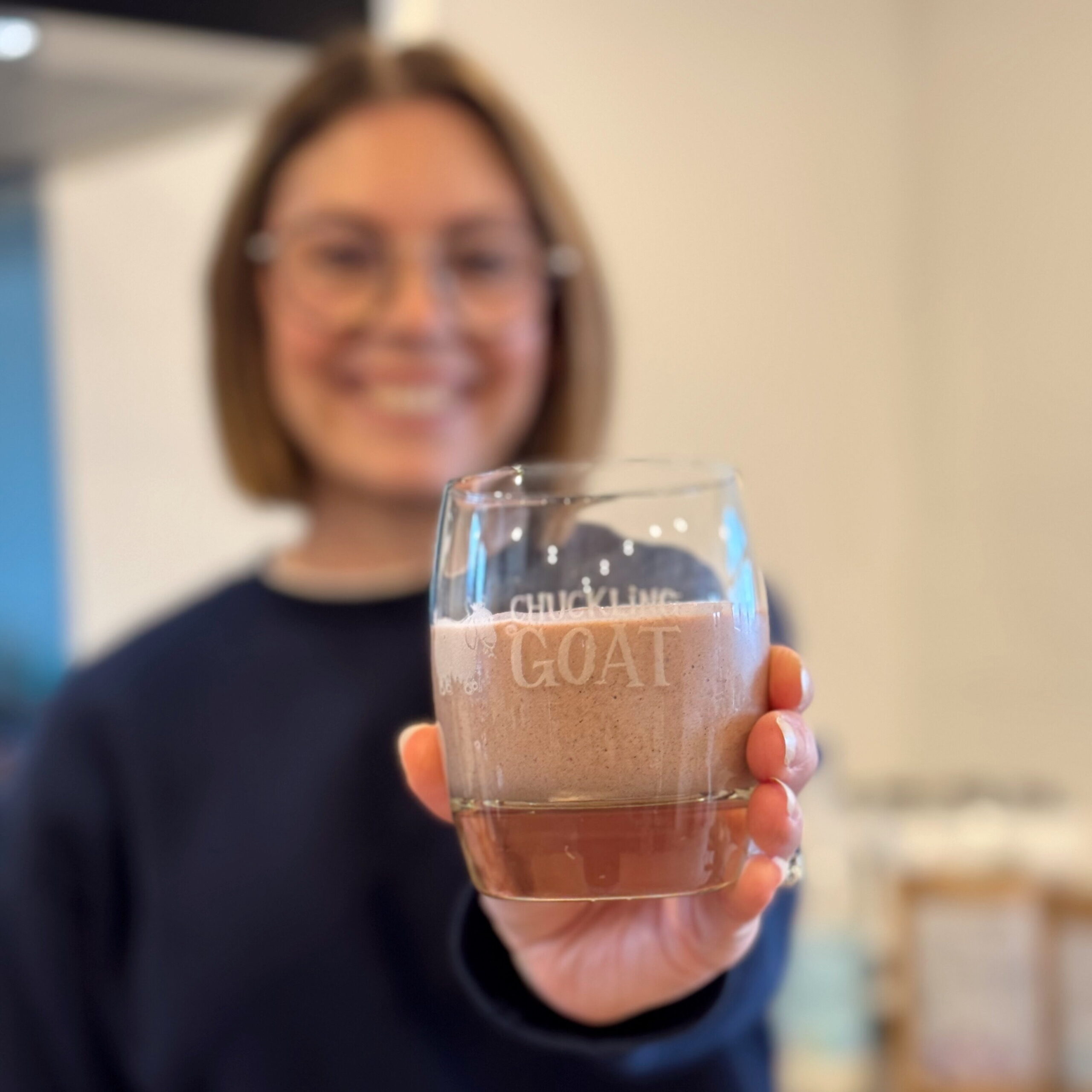 Blurred image of Ceris, Chuckling Goat Director, holding a Chuckling Goat Gut Health Smoothie.