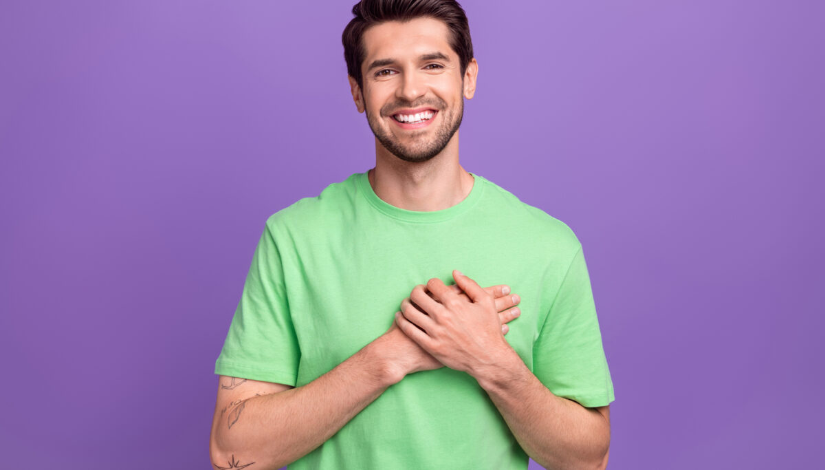 Photo of young smile guy hands touch chest heart thankful grateful appreciate you for support his team isolated on purple colour background.