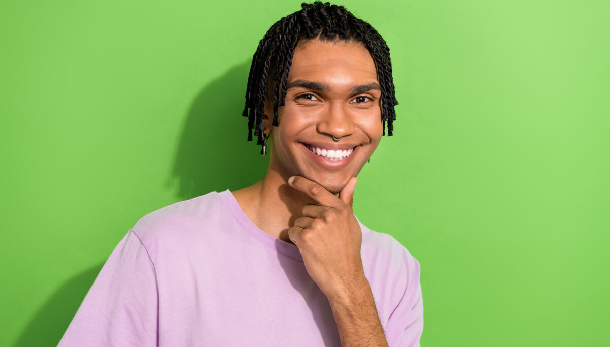 Photo of confident smart man dressed purple t-shirt arm chin smiling isolated green color background.