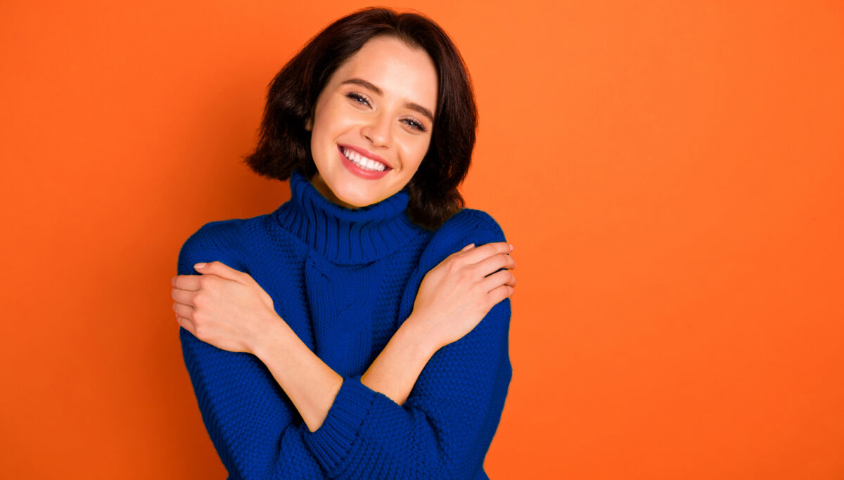 Photo of happy and content woman on an orange background.