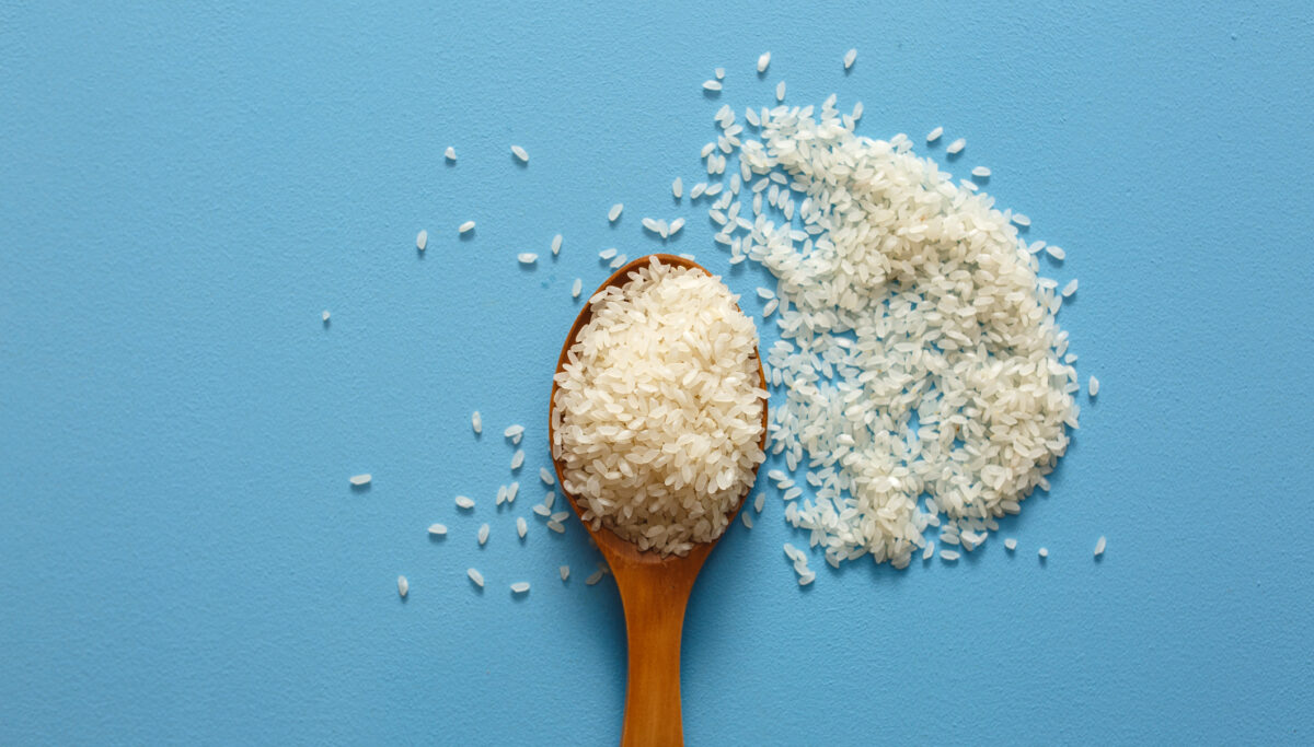 Rice on wooden spoon with blue colour background.