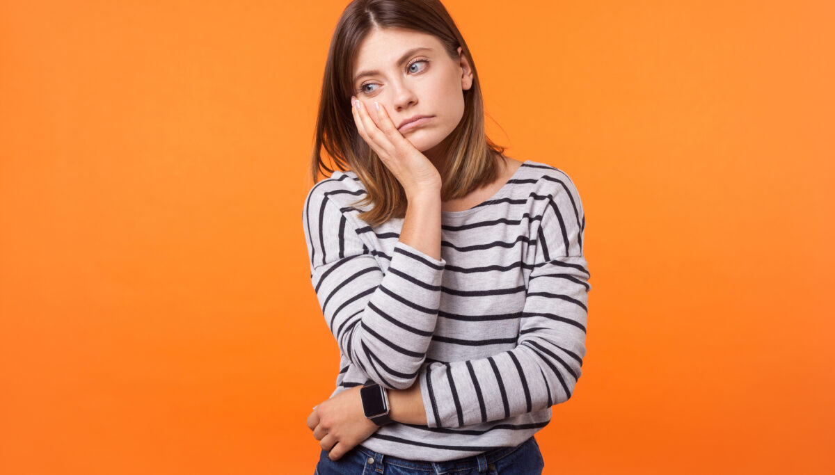 Photo of a woman feeling sluggish, with a sad face on an orange background.