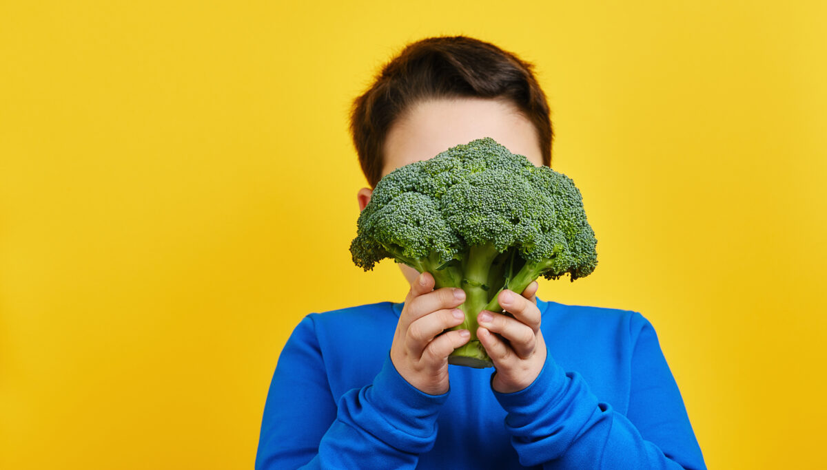 Child holding vegetable on yellow background