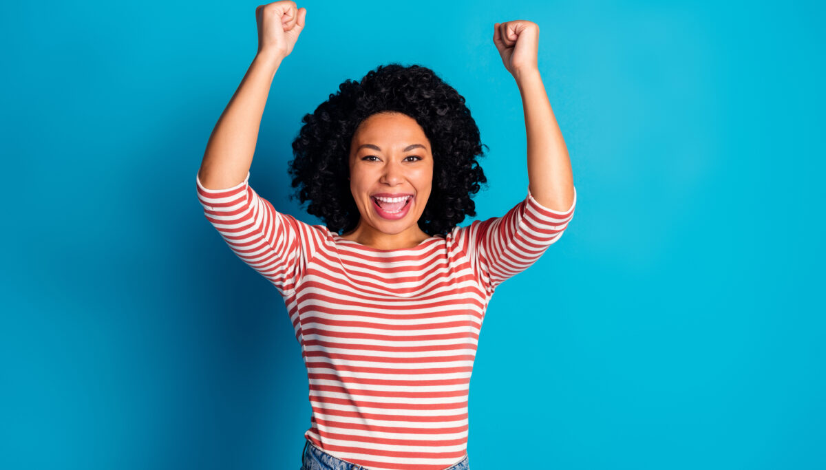 Portrait of pretty lady raise fists shout yes wear striped shirt isolated on blue color background.