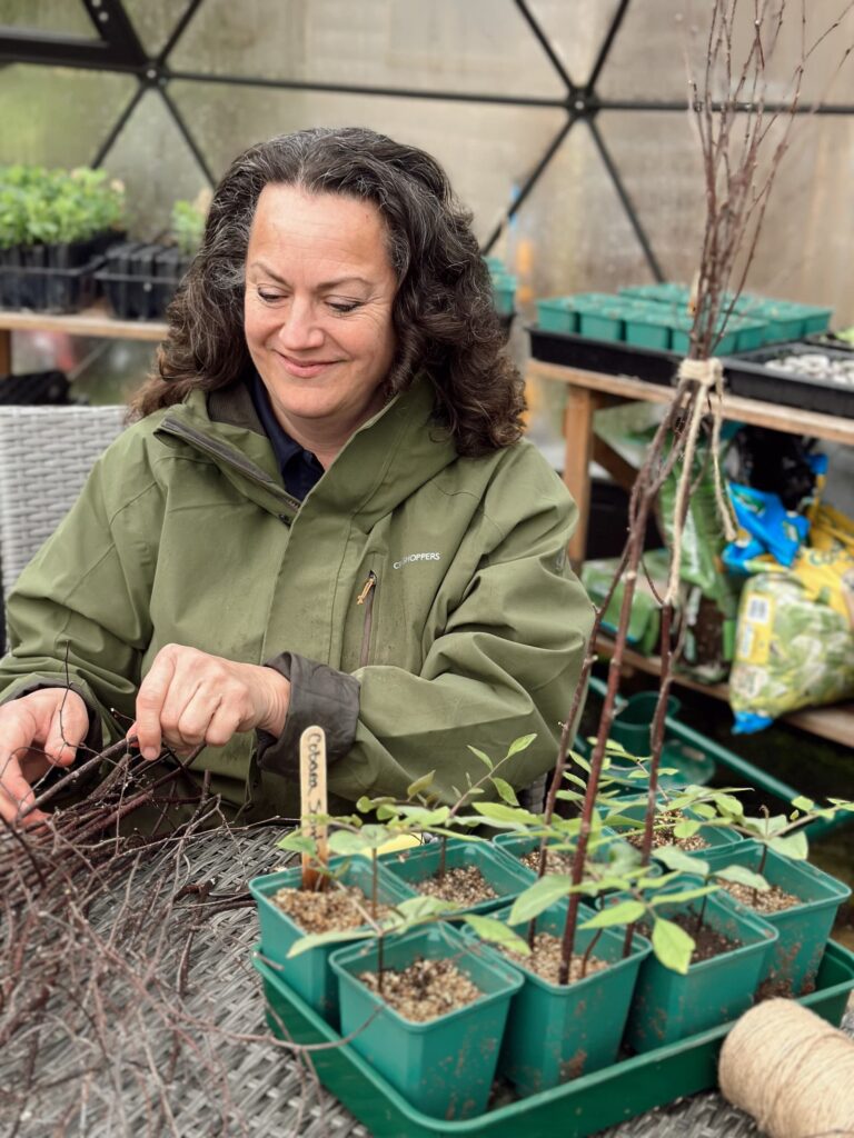 Image of Shann Jones gardening in her greenhouse at Chuckling Goat headquarters and home.