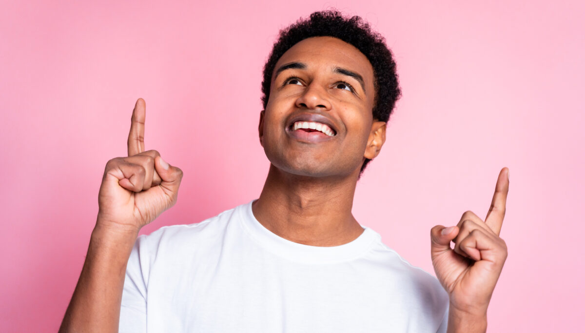 Smiling man looking up and pointing with fingers.