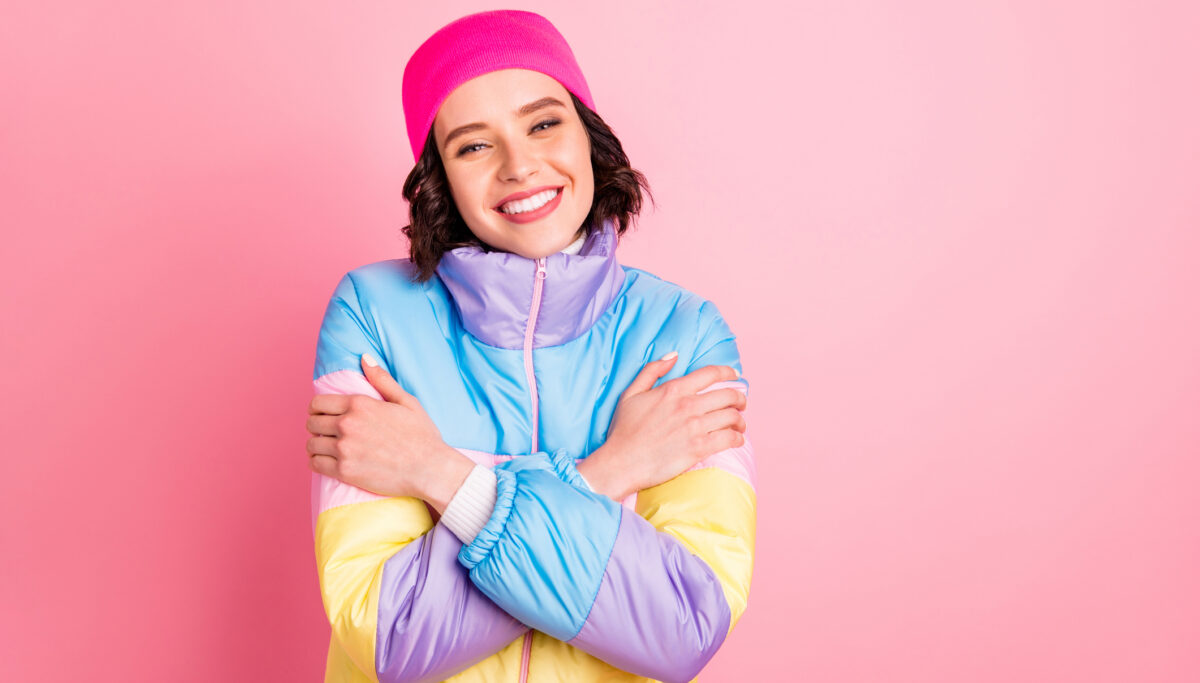 Closeup photo of happy lady, wearing warm coloured coat isolated pink background