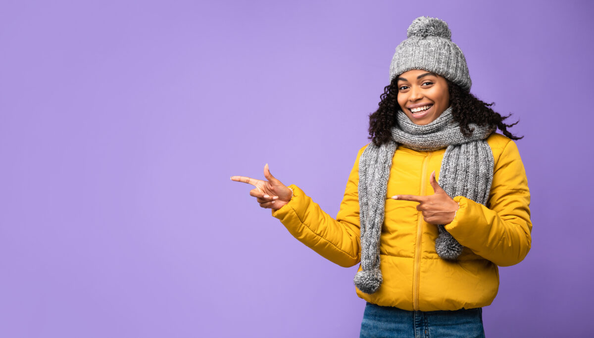 Woman In Winter Jacket Pointing Fingers Purple Studio Background. Winter. Panorama