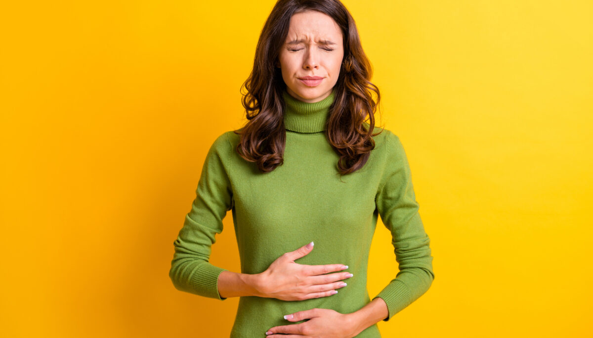 Photo of young woman hold hand on stomach suffers pain pms isolated on yellow background