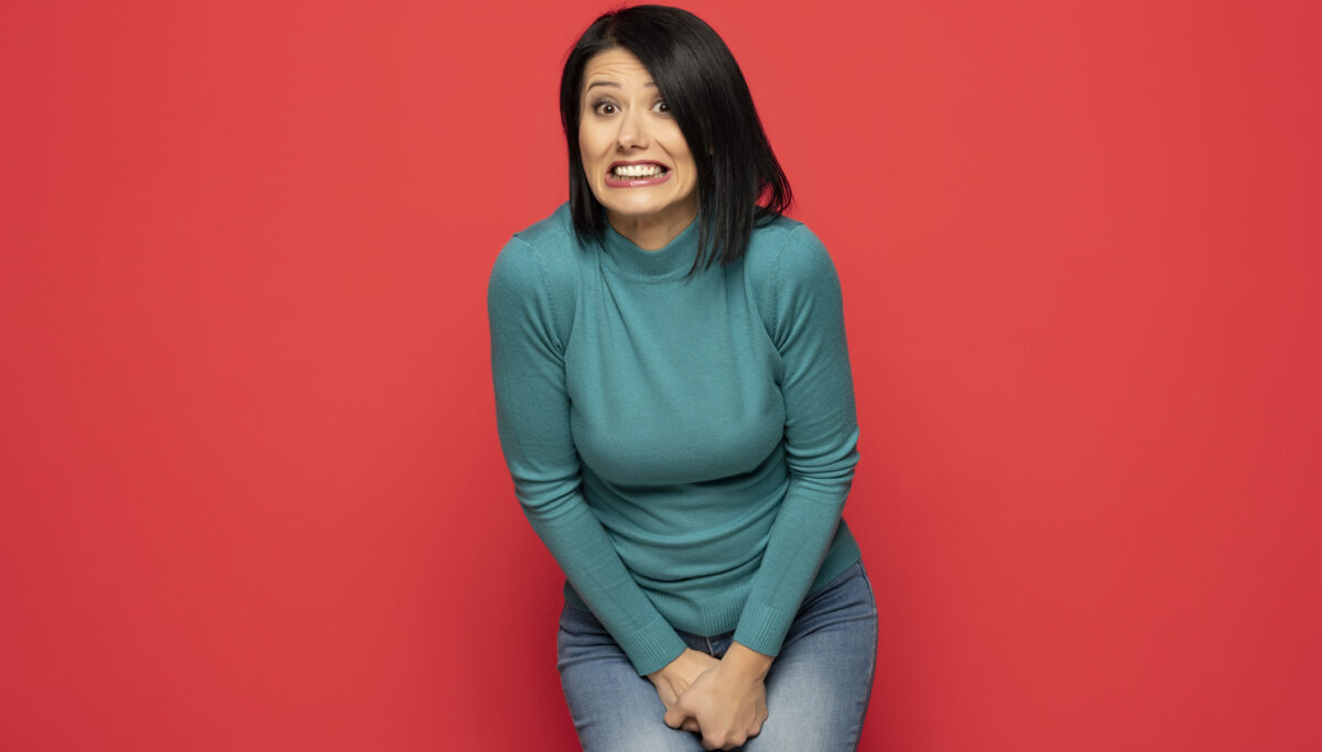 Young woman pressed her hands to the lower abdomen. Red background