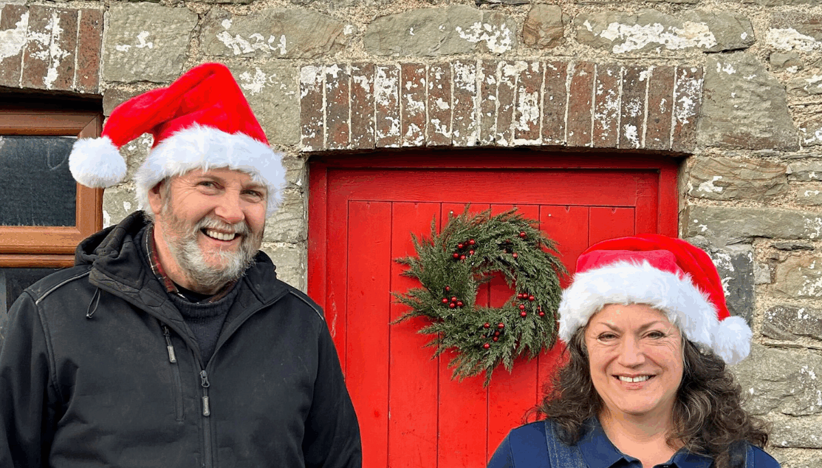 Chuckling Goat directors stood in front of red door with wreath, in festive, Christmas hats.