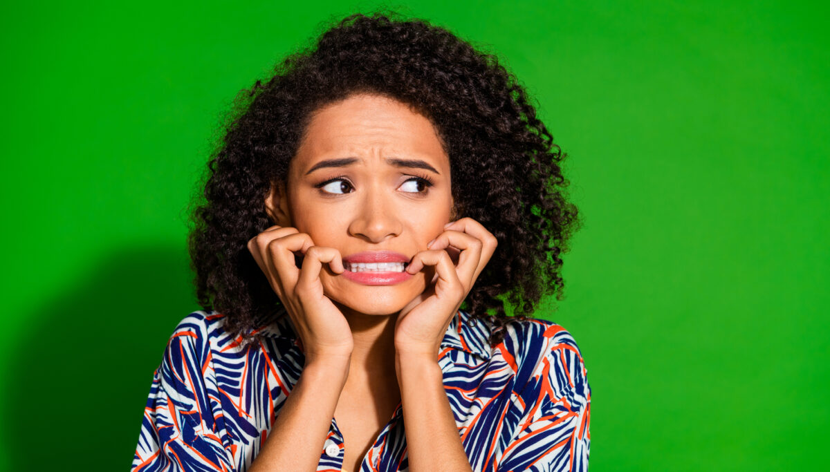 Photo of attractive anxious lady dressed print shirt biting finger look empty space isolated green color background.