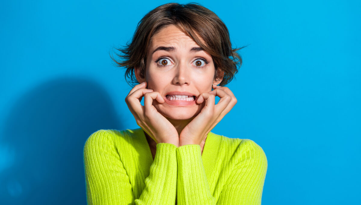 Photo of horrified worried person hands fingers touch cheeks grin teeth empty space isolated on blue color background.