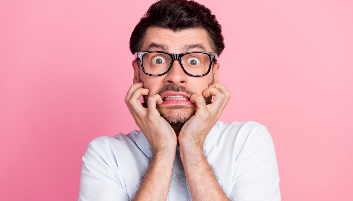 Closeup photo of man bite fingers nails, nervous, anxious, pink background