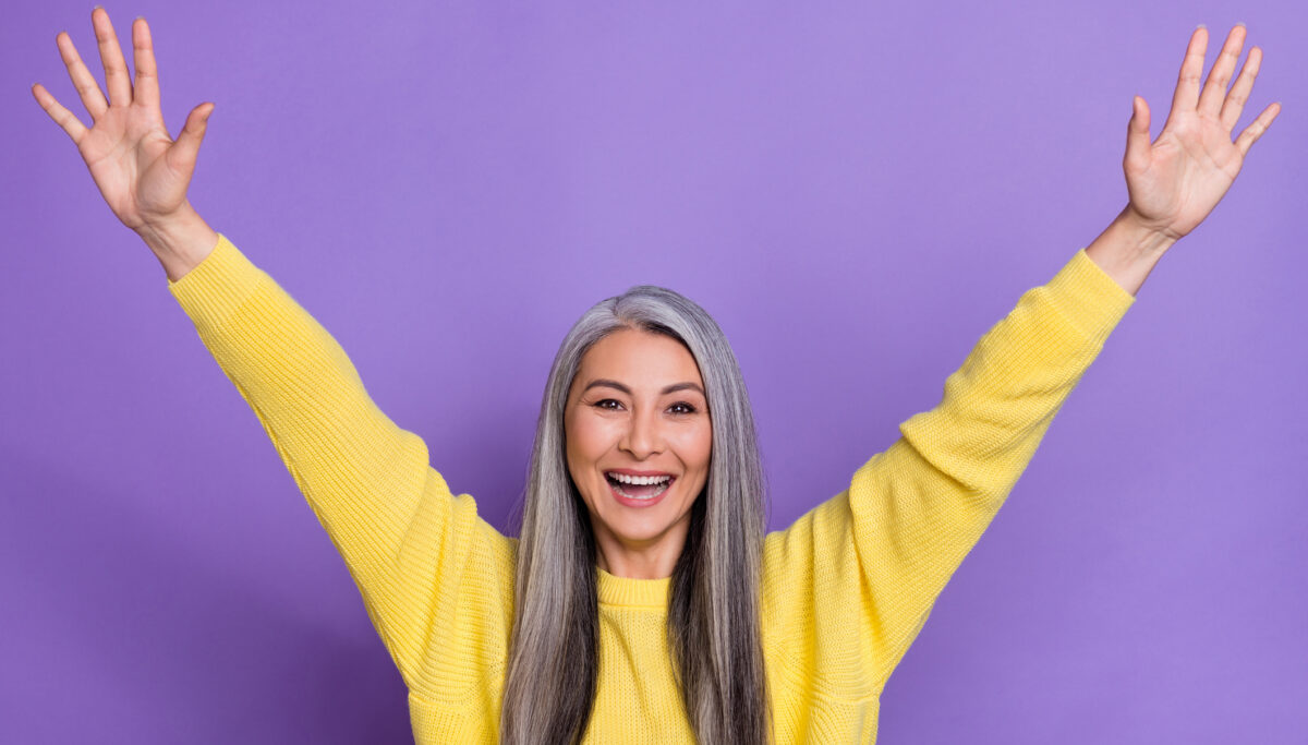 Photo of sweet excited lady pensioner dressed pullover rising arms isolated purple color background.
