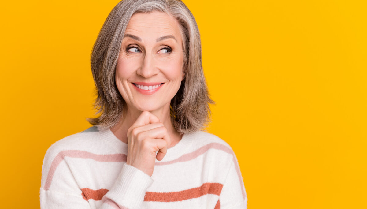 Photo of optimistic, mature lady on yellow color background