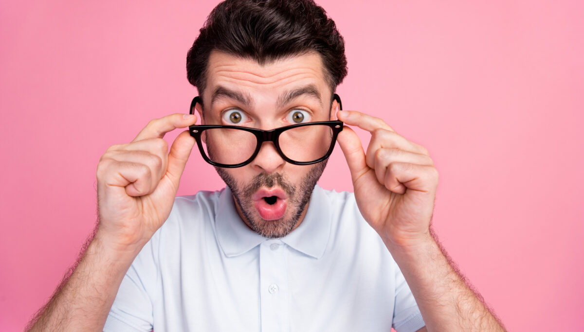 Closeup photo of young handsome shocked funny excited guy wear glasses pouted lips hold spectacles reaction look you isolated on pink color background.