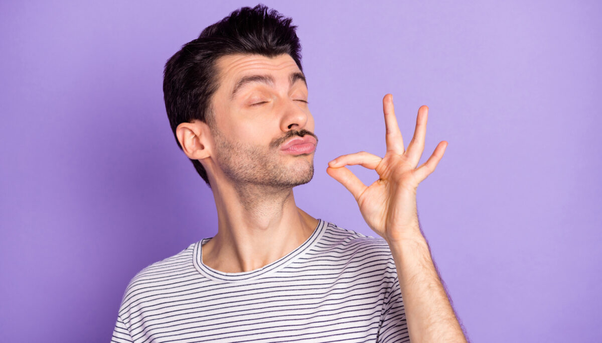 Young man, closed eyes trying delicious tasty food meal isolated on violet color background